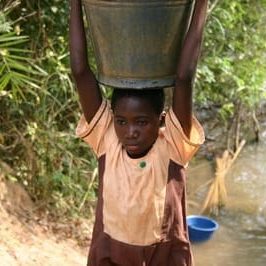 Teen boy carrying water barrel over head